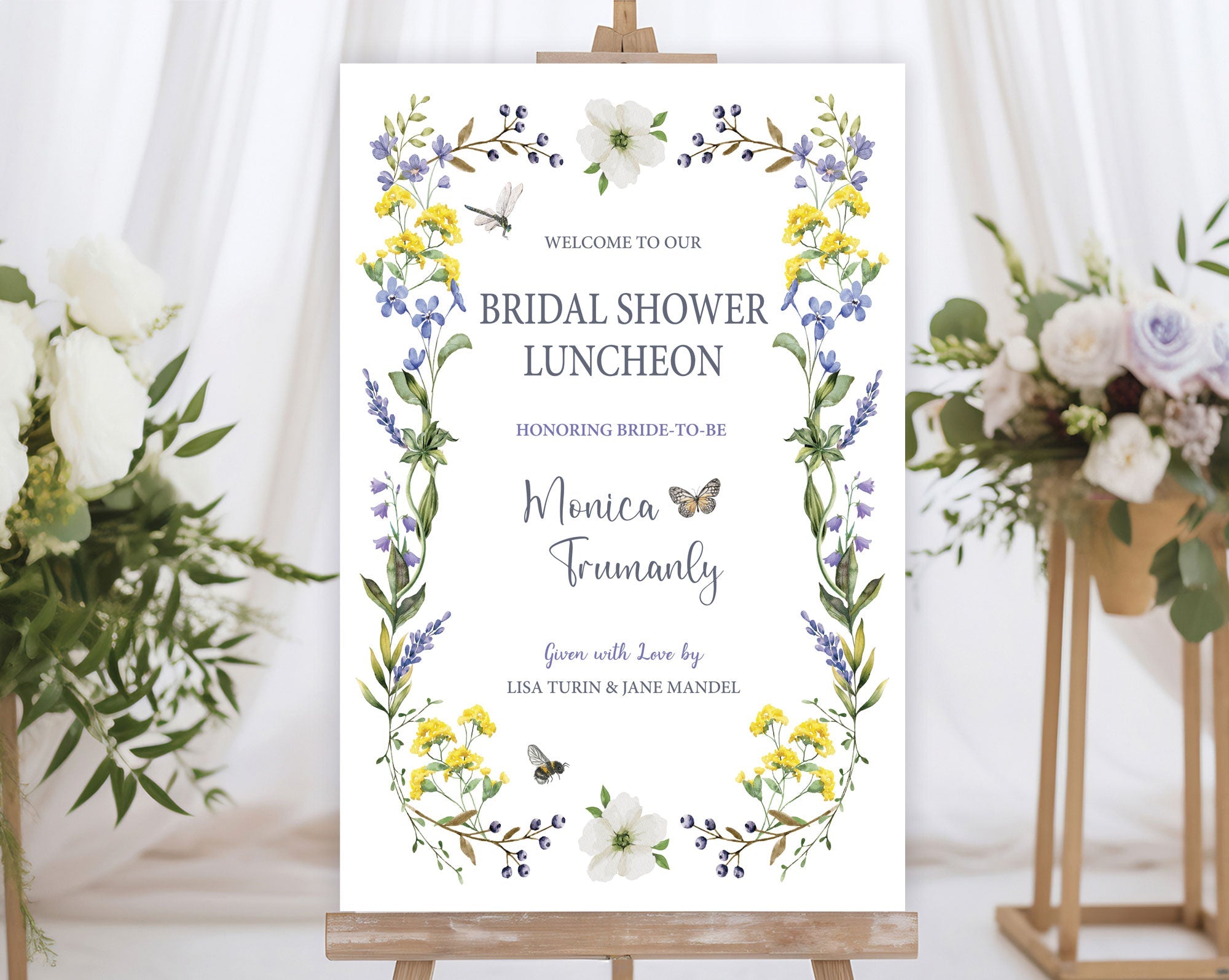 yellow purple wildflower bridal shower welcome sign with bees, dragonfly and butterfly on a wooden easel in front of a white curtain and some flowers on stands