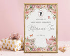 elegant sign for an afternoon tea event with floral design, regency cameo and teapot illustration in a gold frame leaning on a pink background next to a wrapped gift