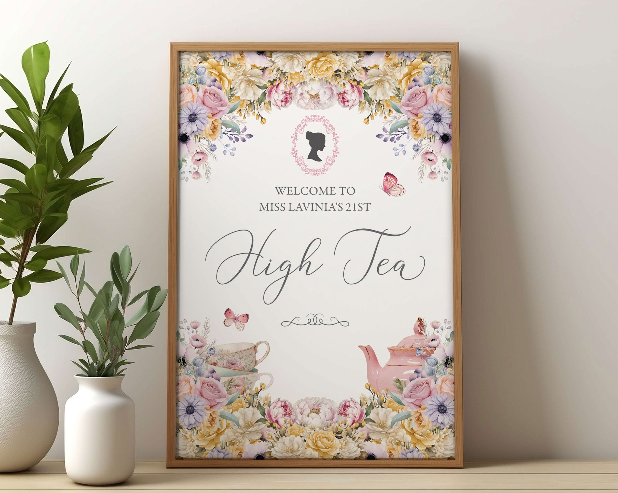 Framed high tea greeting sign with floral design, victorian cameo leaning on a white wall.