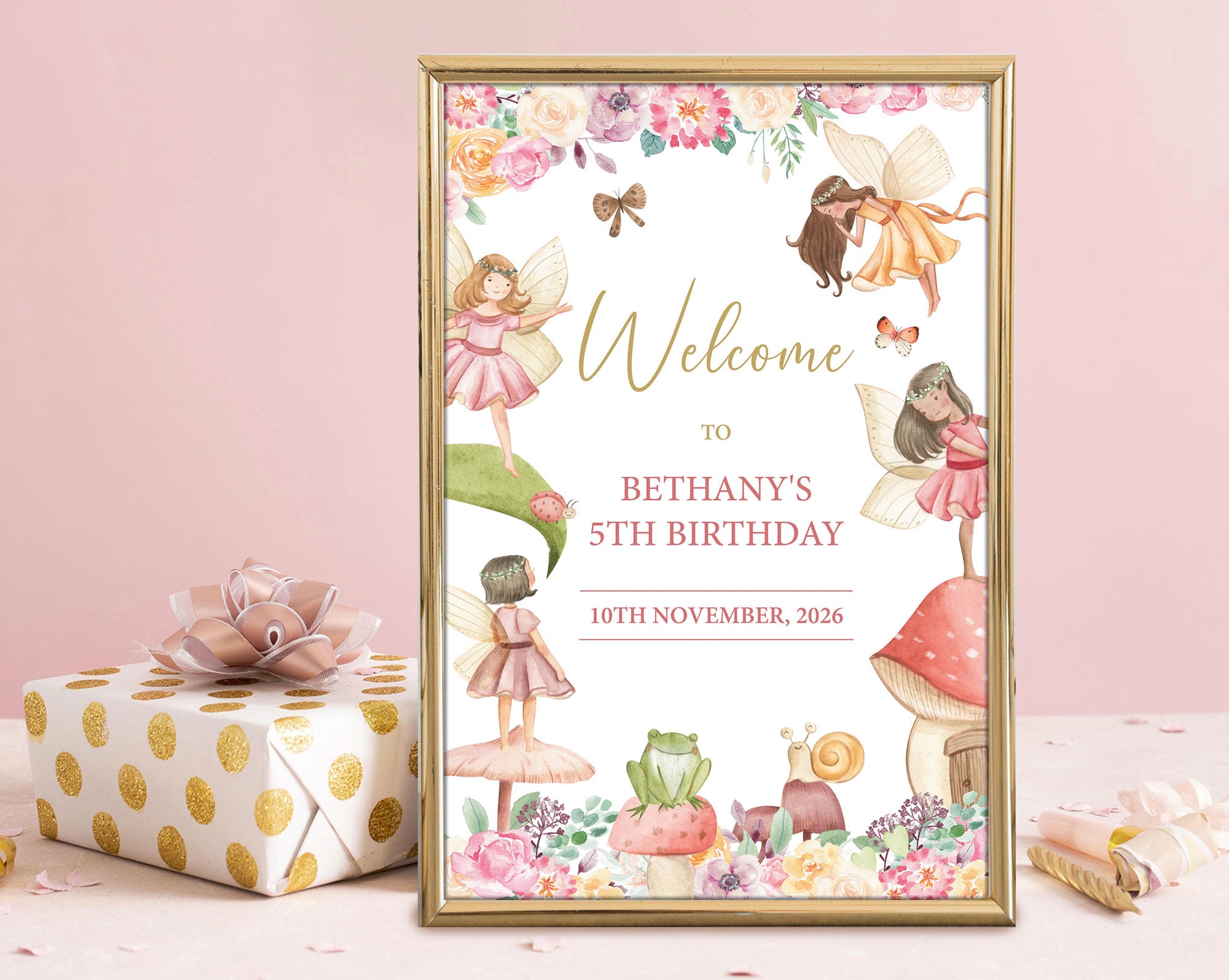a fairy party welcome sign in a gold frame leaning up against a pink wall next to a wrapped gift