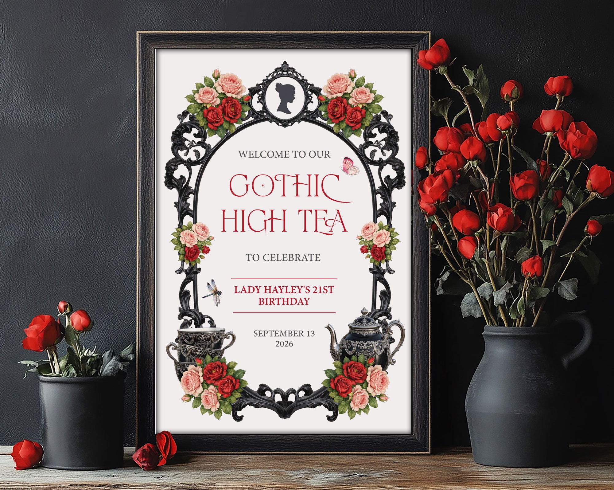 Elegant moody A4 Gothic High Tea Welcome Sign with regency style cameo, red pink flowers and teapot in a black frame leaning against a black wall next to vases of red roses