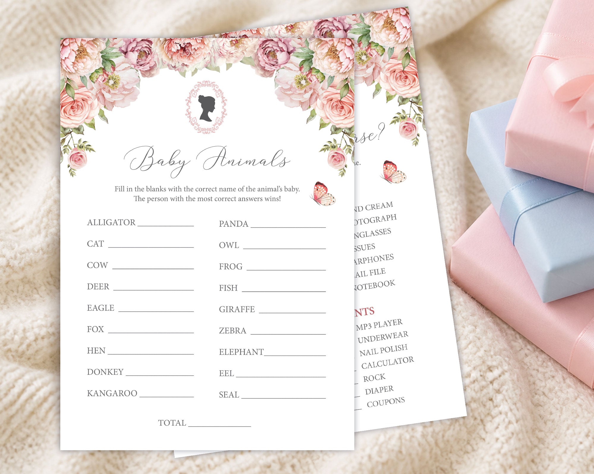 two blush pink baby shower game cards, one titled 'baby shower feud' laying on a cream blanket next to some pink and blue wrapped gifts