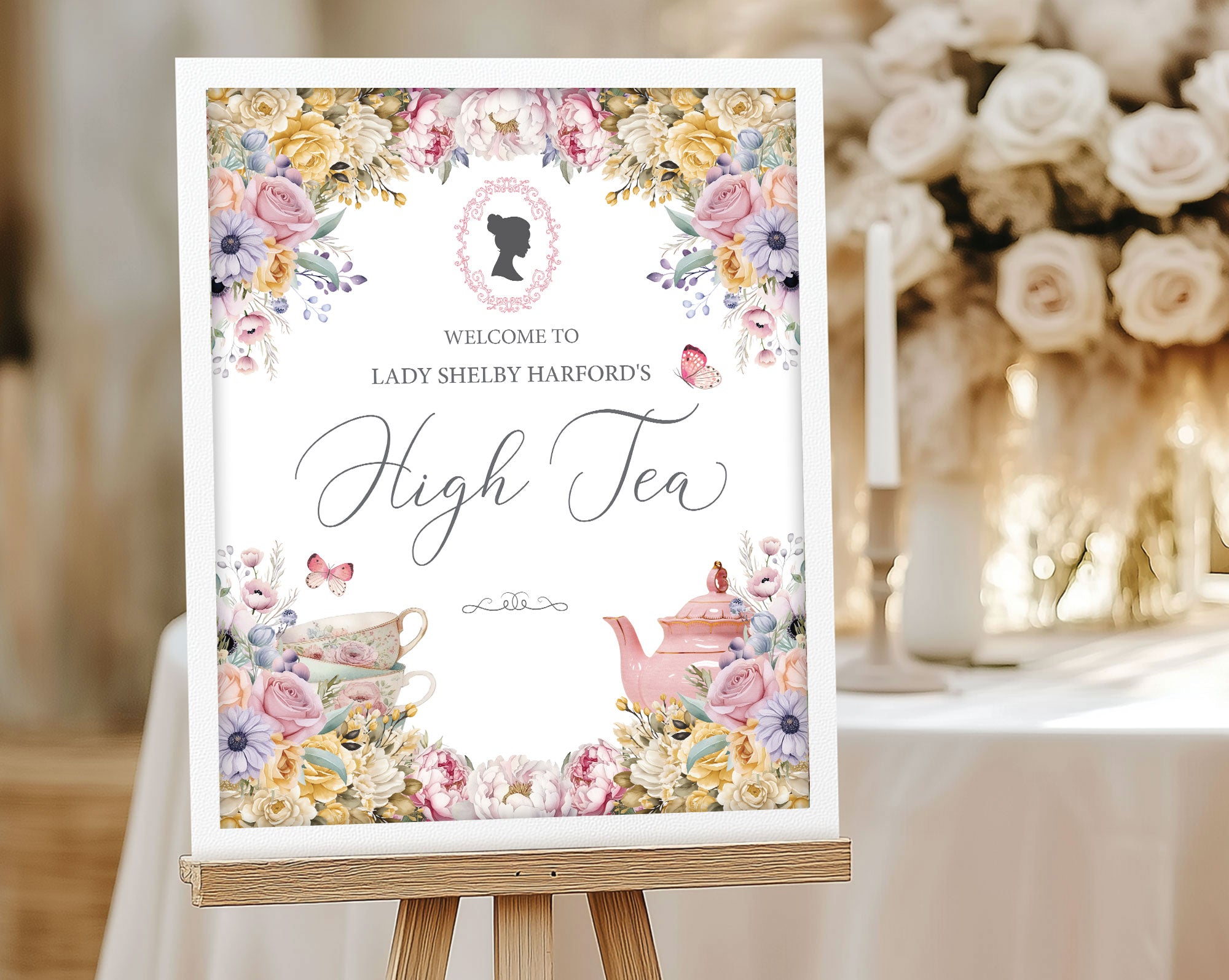 Decorative high tea welcome sign with floral and teapot designs on a wooden easel.