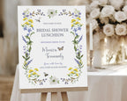 a wildflower welcome sign with butterfly, dragonfly and bee, on a wooden easel, in front of a table with candles and white flowers
