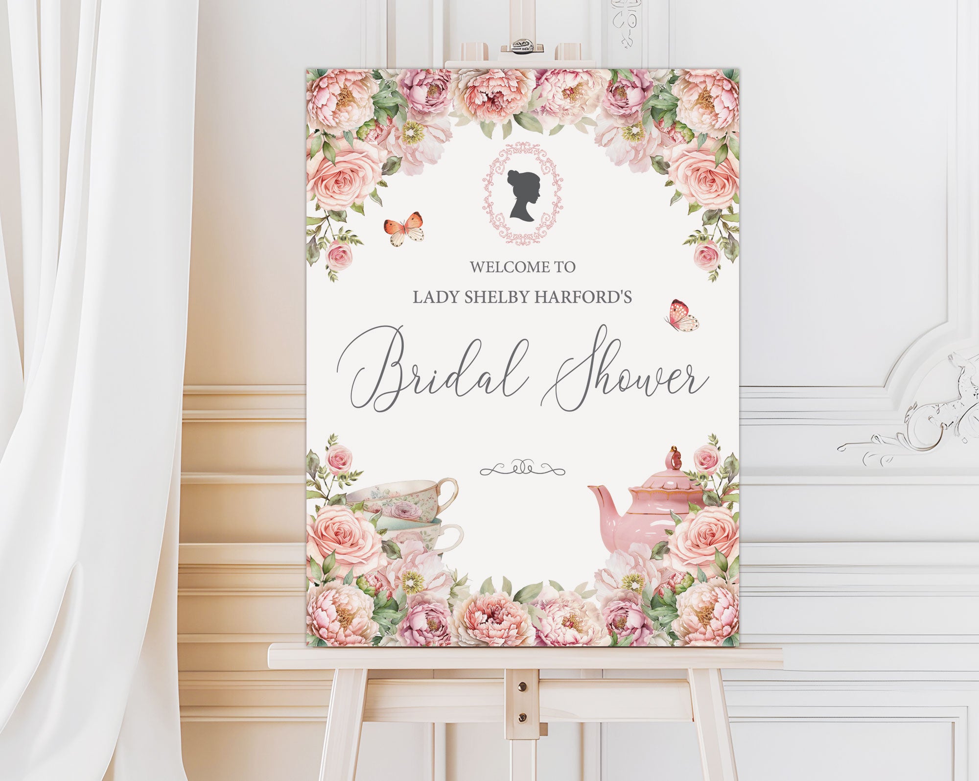 elegant blush pink entrance sign for a bridal shower with teapot and cameo on a wooden easel in front of a white panelled wall and curtain