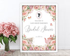 pretty blush pink flower regency inspired welcome sign with cameo, teapot and butterfly graphics, in a white frame, leaning up against a white wall, next to a vase with pink flowers