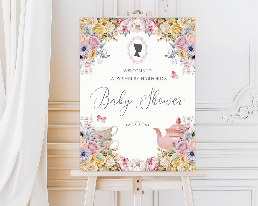 elegant pastel entrance sign for a baby shower with teapot and cameo on a wooden easel in front of a white panelled wall and curtain