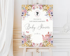elegant pastel entrance sign for a baby shower with teapot and cameo on a wooden easel in front of a white panelled wall and curtain