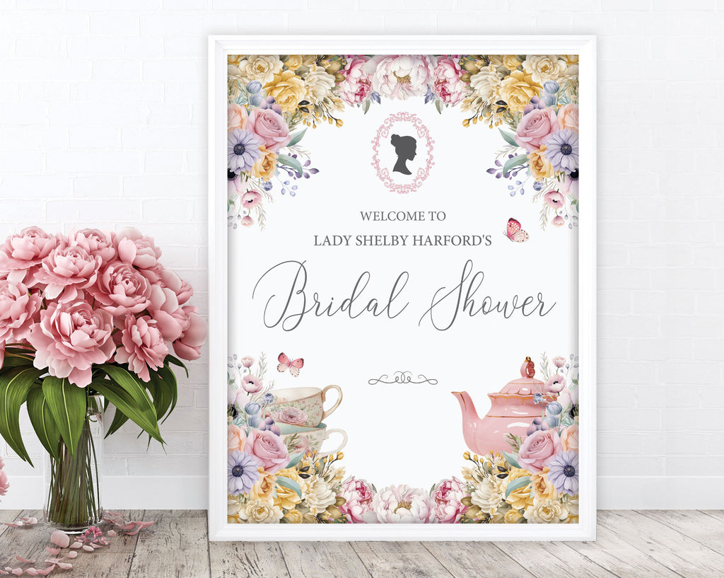 pretty blush pink flower regency inspired welcome sign with cameo, teapot and butterfly graphics, in a white frame, leaning up against a white wall, next to a vase with pink flowers