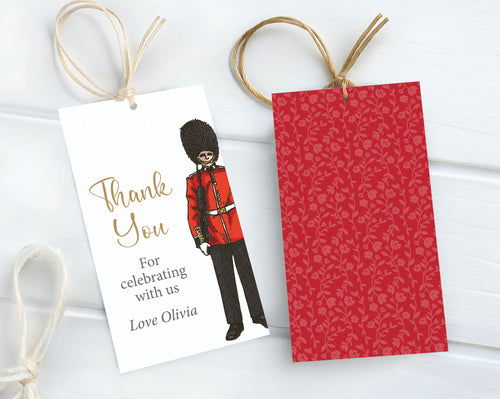 two london icon favor tags, one with the Royal Guard graphic and one showing the red pattern back, each with some string attached laying on a white wooden background