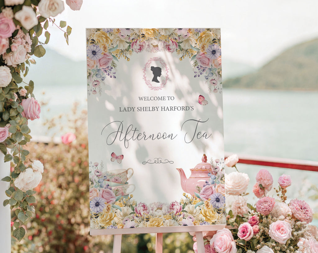 pastel flower welcome sign for an afternoon tea event with regency style cameo, outside with a seascape background and surrounded by pink flowers