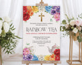 church ladies 24 x 36 rainbow tea welcome sign with gold cross graphic on a wooden easel in front of a white curtain and some flowers on stands