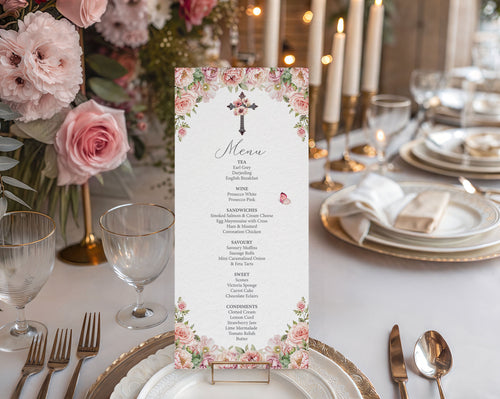 blush pink flower church event menu with christian cross in a gold stand on a white table set for a dinner