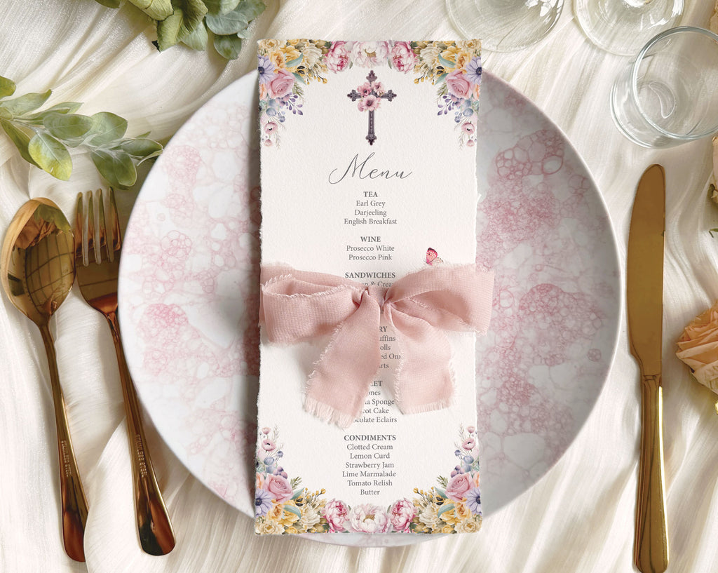 pretty pastel religious Menu card with floral design and cross on a table setting with plates, cutlery, and glasses.