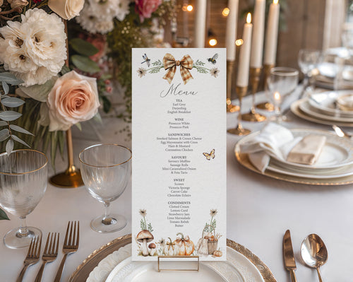 A vertical menu card with a rustic autumn theme, displayed on a table setting. The menu features a brown gingham bow illustration at the top and illustrations of pumpkins, mushrooms, and wildflowers at the bottom.