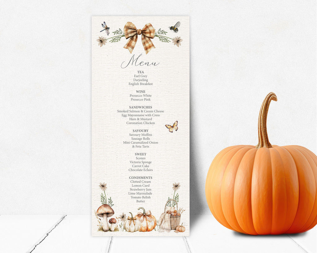 A vertical fall-themed menu card leaning up against a  white wall next to a whole orange pumpkin. The menu card features a brown gingham bow illustration at the top, cursive 'Menu' text, a list of course items, and small autumn illustrations including pumpkins, mushrooms, and butterflies at the bottom.