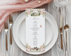 Jane Austen inspired floral menu card with mansion and book graphics laying on a white plate on a wooden table.