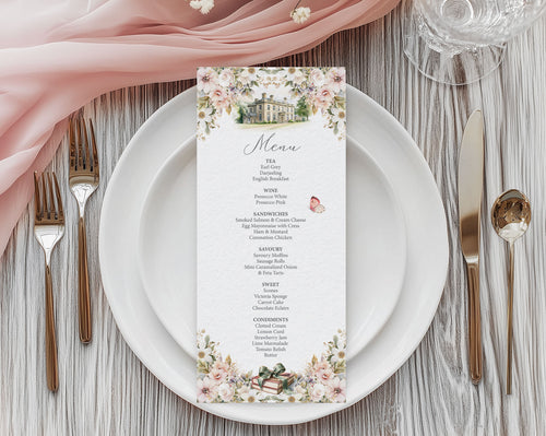 Jane Austen inspired floral menu card with mansion and book graphics laying on a white plate on a wooden table.