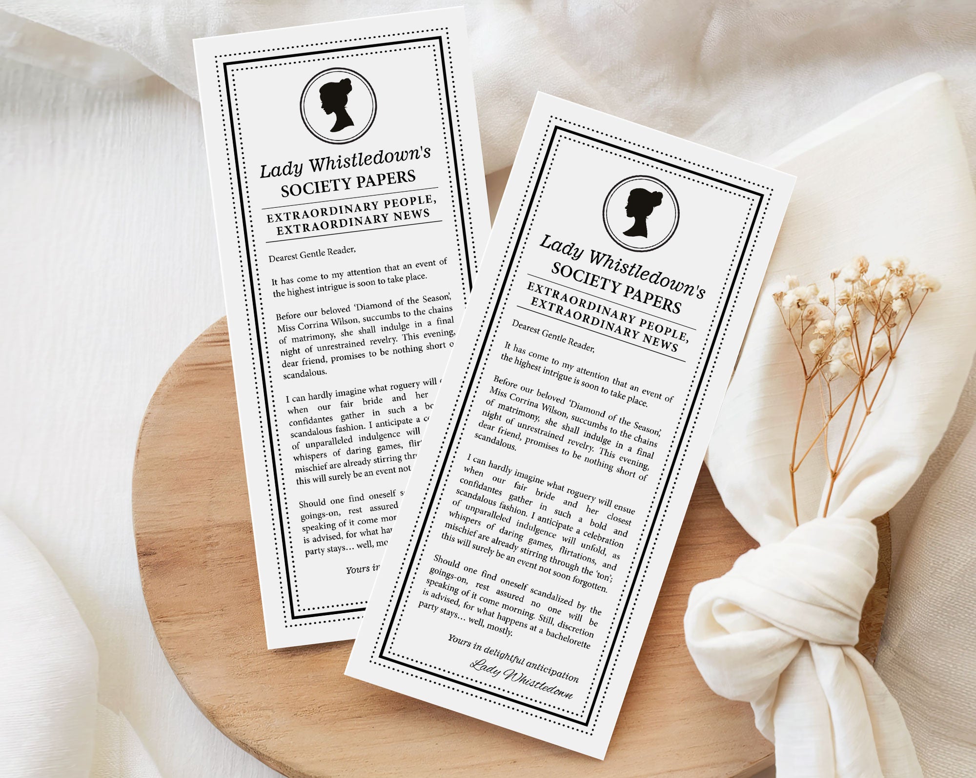 two 'Lady Whistledown's Society Bachelorette Party Announcement Papers' on a wooden surface with a white fabric background.