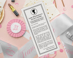 pretty black and white regency style society notice for Bachelorette party sitting on patterned white dinner plates next to a serviette with black bow