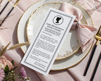 a black and white regency style girls birthday regency style announcement card laying on a gold and white plate with a pink bow and flowers next to it