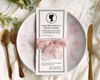 Pretty Dear Gentle Reader Ton Kids birthday Society announcement wrapped in a pink ribbon on a plate sitting on a silk white background with gold fork and knife