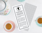 Tea cup with a printed 'Lady Whistledown's Society Papers' with regency cameo on a white surface.
