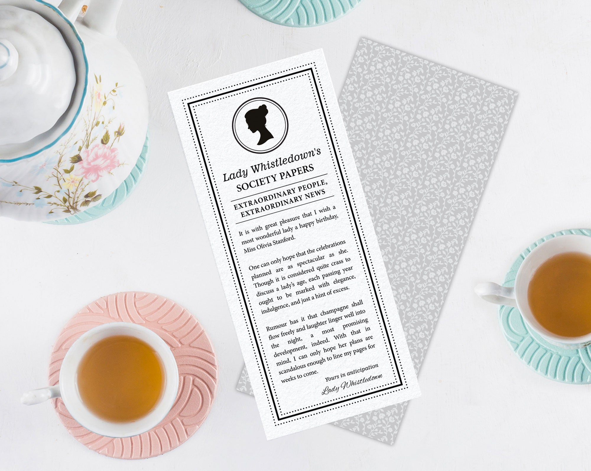 Tea cup with a printed 'Lady Whistledown's Society Papers' with regency cameo on a white surface.