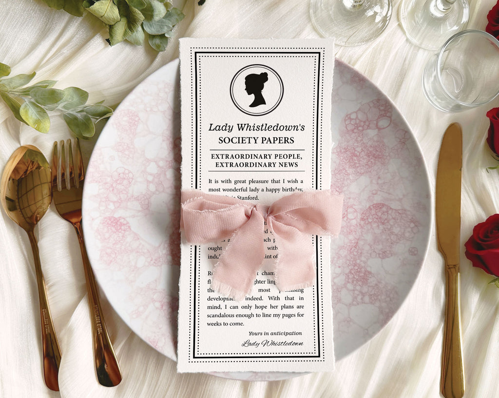 Table setting featuring 'Lady Whistledown's Society Papers' with bridgerton inspired cameo wrapped with a ribbon on a decorative plate.