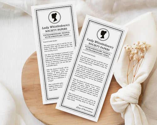 two 'Lady Whistledown's Society Bridal Shower Announcement Papers' on a wooden surface with a white fabric background.