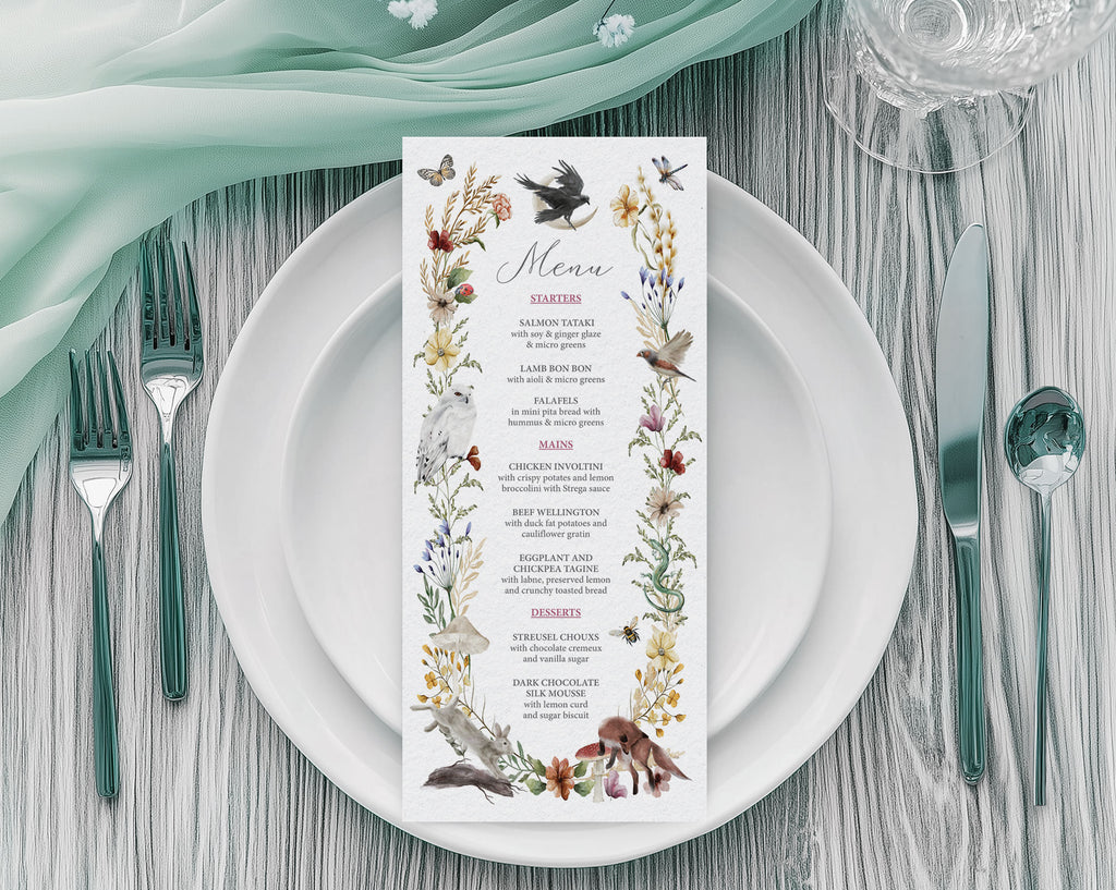 A 4 x 9 Menu for an enchanted forest party with woodland animals and raven graphics laying on a white plate with cutlery
