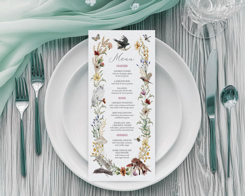 A 4 x 9 Menu for an enchanted forest party with woodland animals and raven graphics laying on a white plate with cutlery