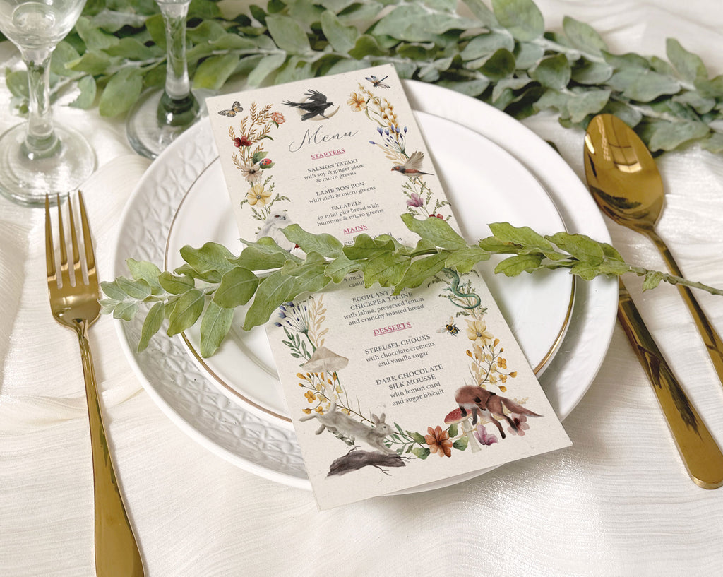 recycled style dinner menu laying on a white plate with greenery across the front and also in the background