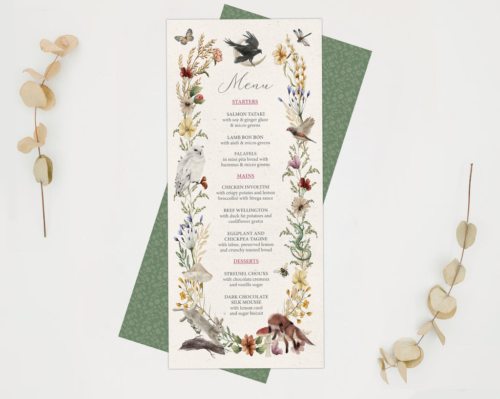 a pretty enchanted forest dinner menu with various woodland animals and bird graphics laying on the green menu back on a white background