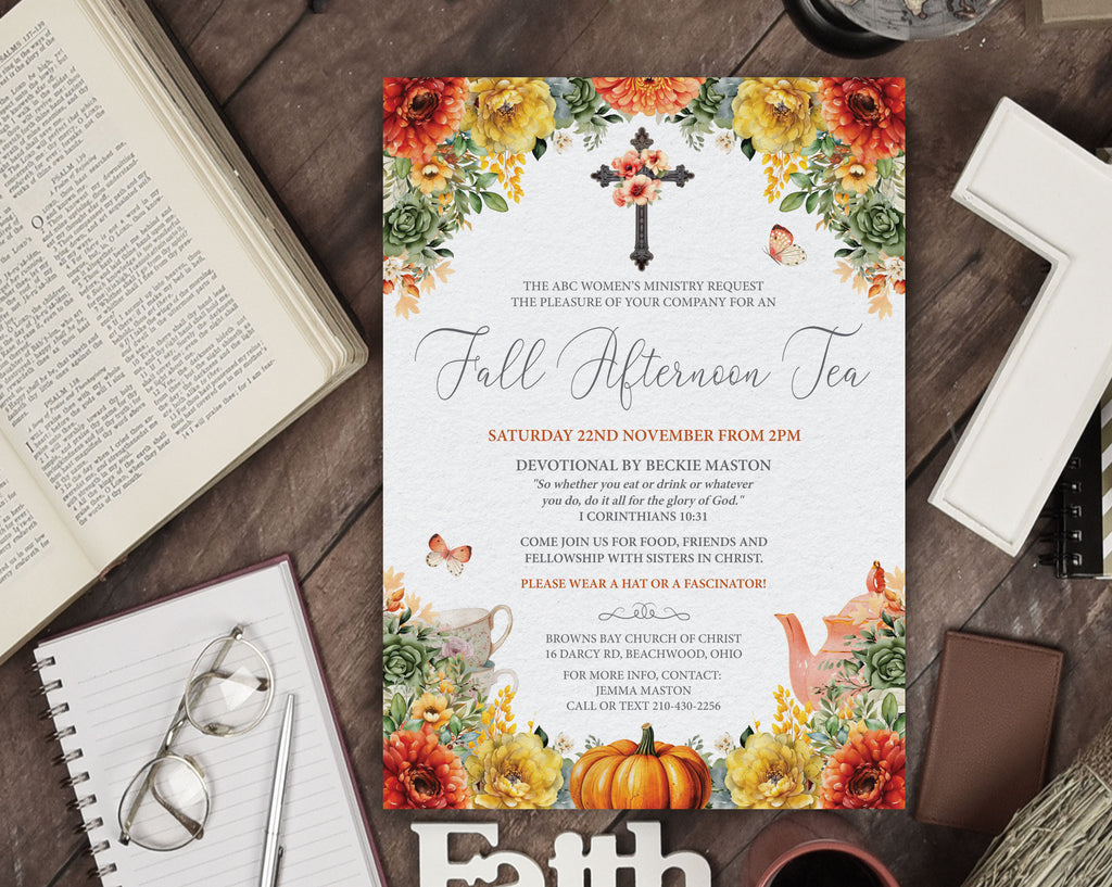 A fall afternoon tea invitation card with autumn floral borders, a cross and nativity design, and event details, styled on a dark wood tabletop with an open Bible, notebook, glasses, and other seasonal props.