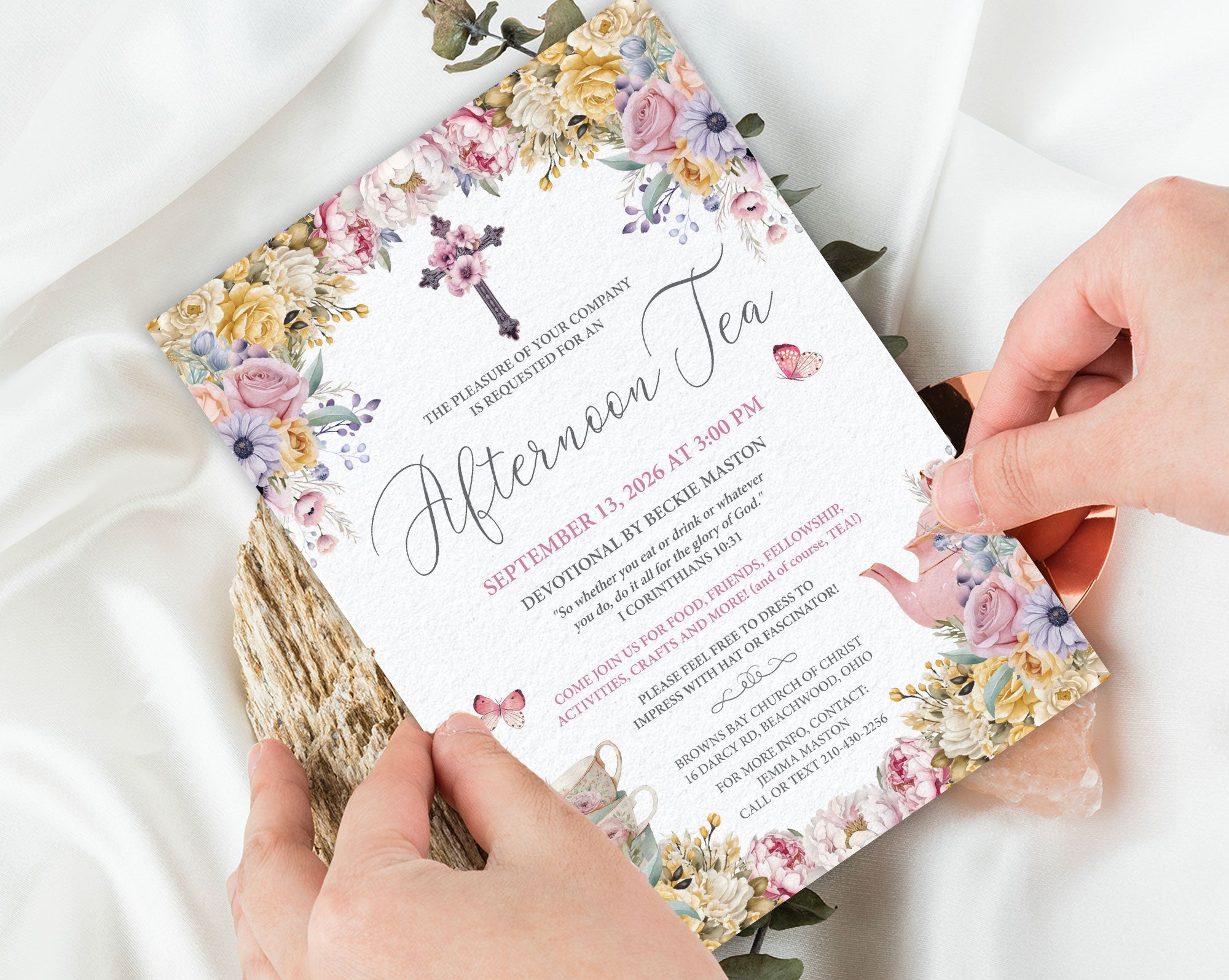 pastel Floral invitation card for a church tea with scripture held by a person on a white fabric background