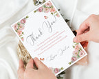 Card with floral design and text held by hands on a light background