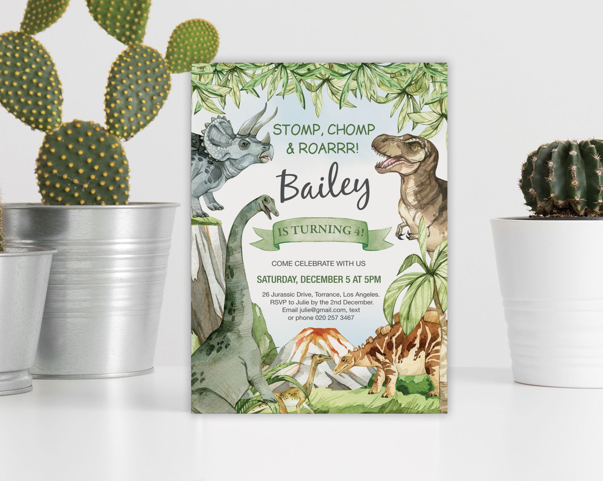 Dinosaur-themed birthday invitation leaning against a white wall next to cacti in pots