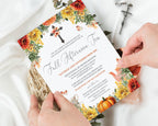 A floral fall afternoon tea invitation card is being held by two hands over white satin fabric, with a small cross and wrapped gift box nearby.