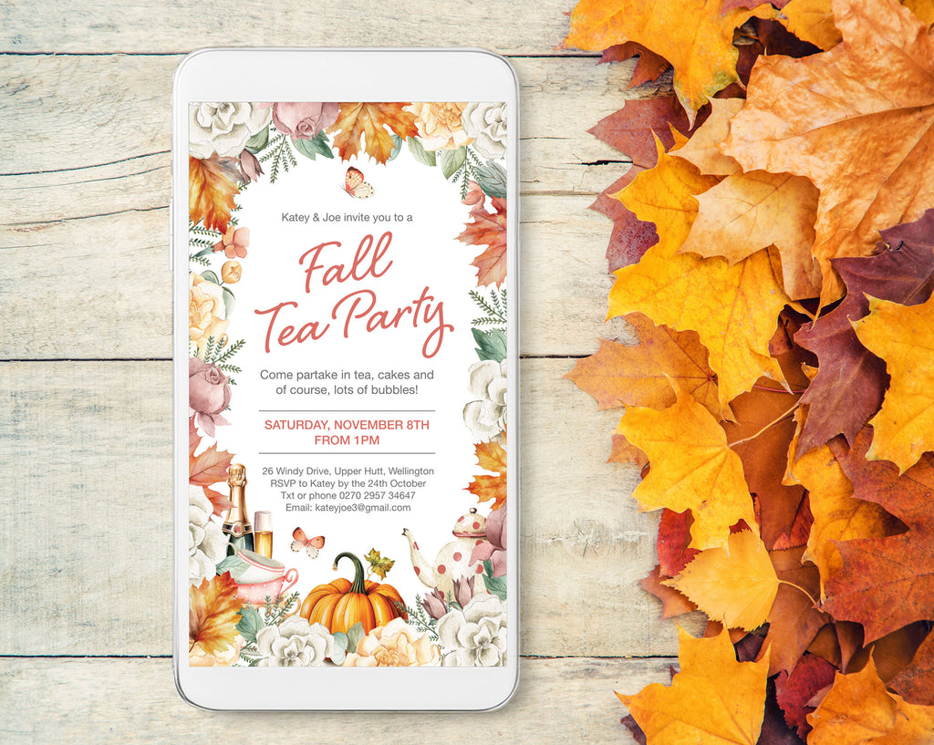 A smartphone mockup displays a fall tea party invitation with floral and autumn-themed graphics, placed on a light wood surface next to scattered orange and yellow leaves.