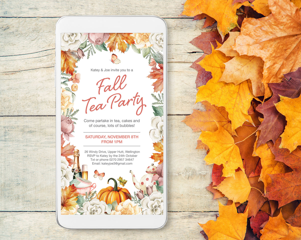 A smartphone mockup displays a fall tea party invitation with floral and autumn-themed graphics, placed on a light wood surface next to scattered orange and yellow leaves.