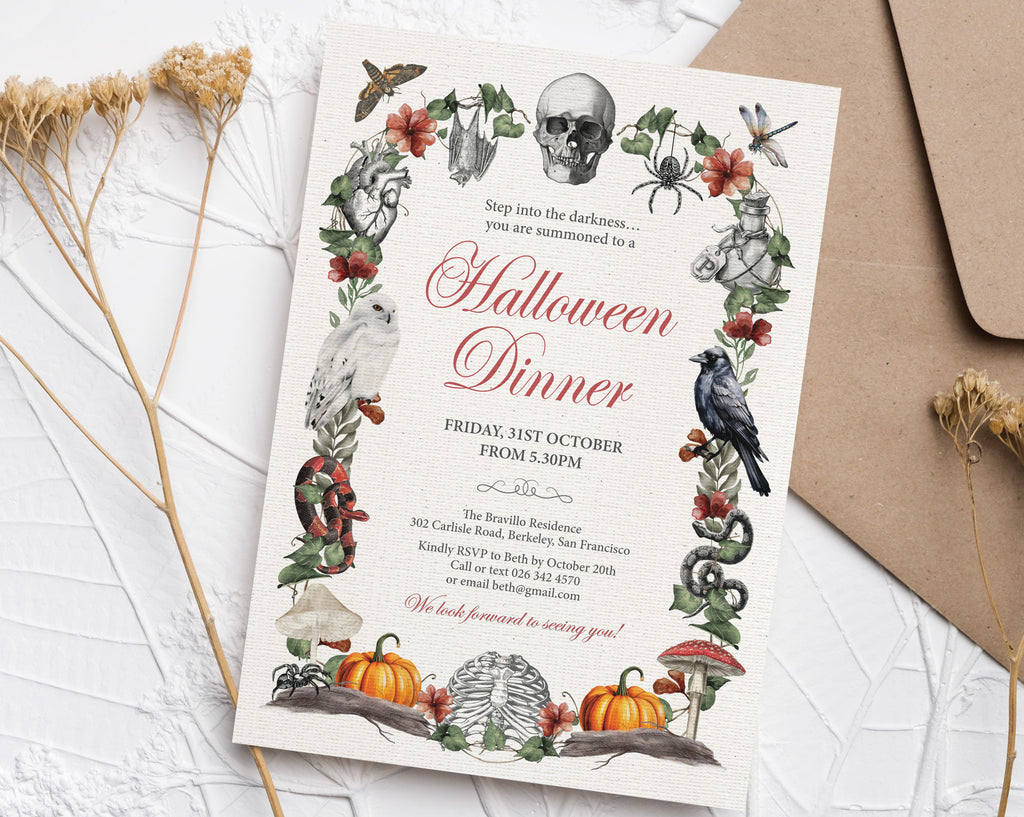 A Halloween dinner invitation card with a dark gothic illustration border featuring a skull, spider, owl, crow, mushrooms, and pumpkins, styled on a white textured surface with dried grass and a kraft envelope.