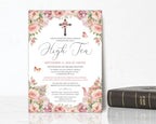 High tea invitation with floral design and cross, placed on a white surface with a Bible below.
