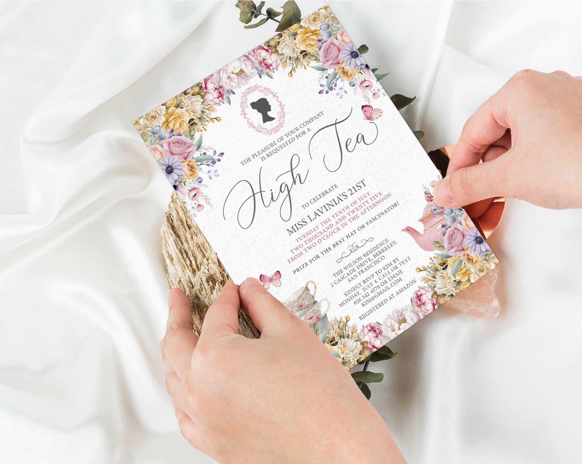 Regency Style Floral invitation card held by hands on a white fabric background