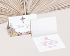 Thank you card with pastel floral design and a cross, one open so you can see the text, placed on a textured surface.
