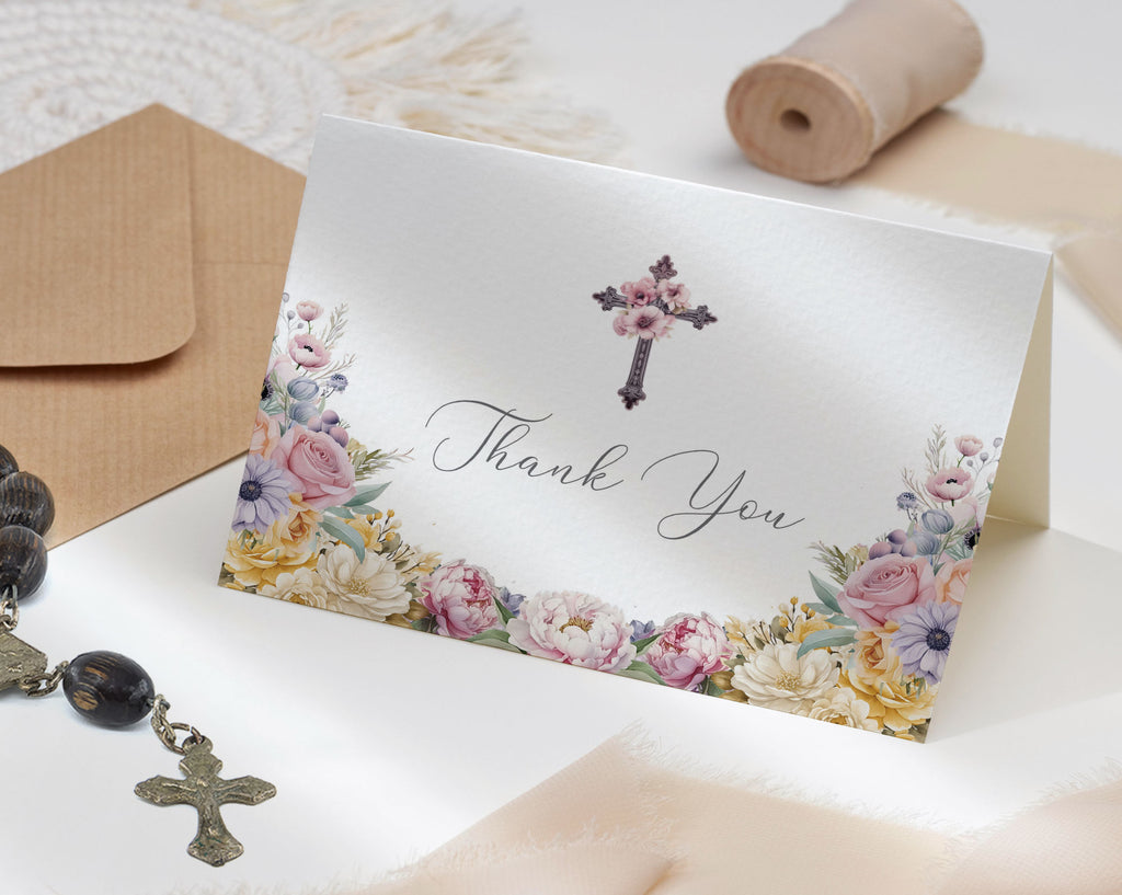 church thank you tent card with floral design and cross, placed on a textured surface with ribbon roll, envelope and rosary.