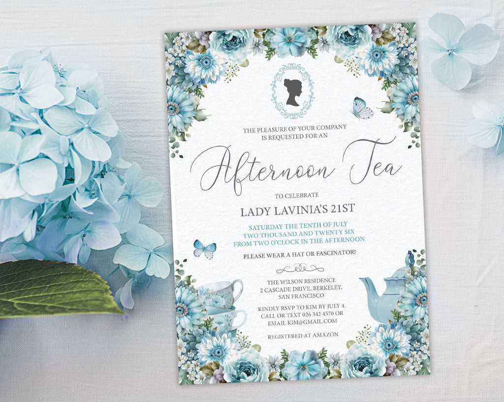elegant dusty blue flower Invitation card for an afternoon tea celebration on a white surface next to blue hydrangea