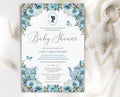 regency baby shower invitation with cameo, teapot and dusty blue flowers laying on a white cloth with a knitted baby pacifier next to it