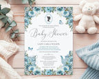 an elegant blue baby shower tea regency style invitation laying on the pink pattern back of the invite, on a white cloth with a white teddy bear and a wrapped gift