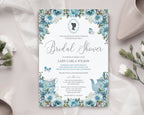 Pretty dusty blue flower bridal shower invitation laying on a beige silk background with a wedding shoe and some flowers
